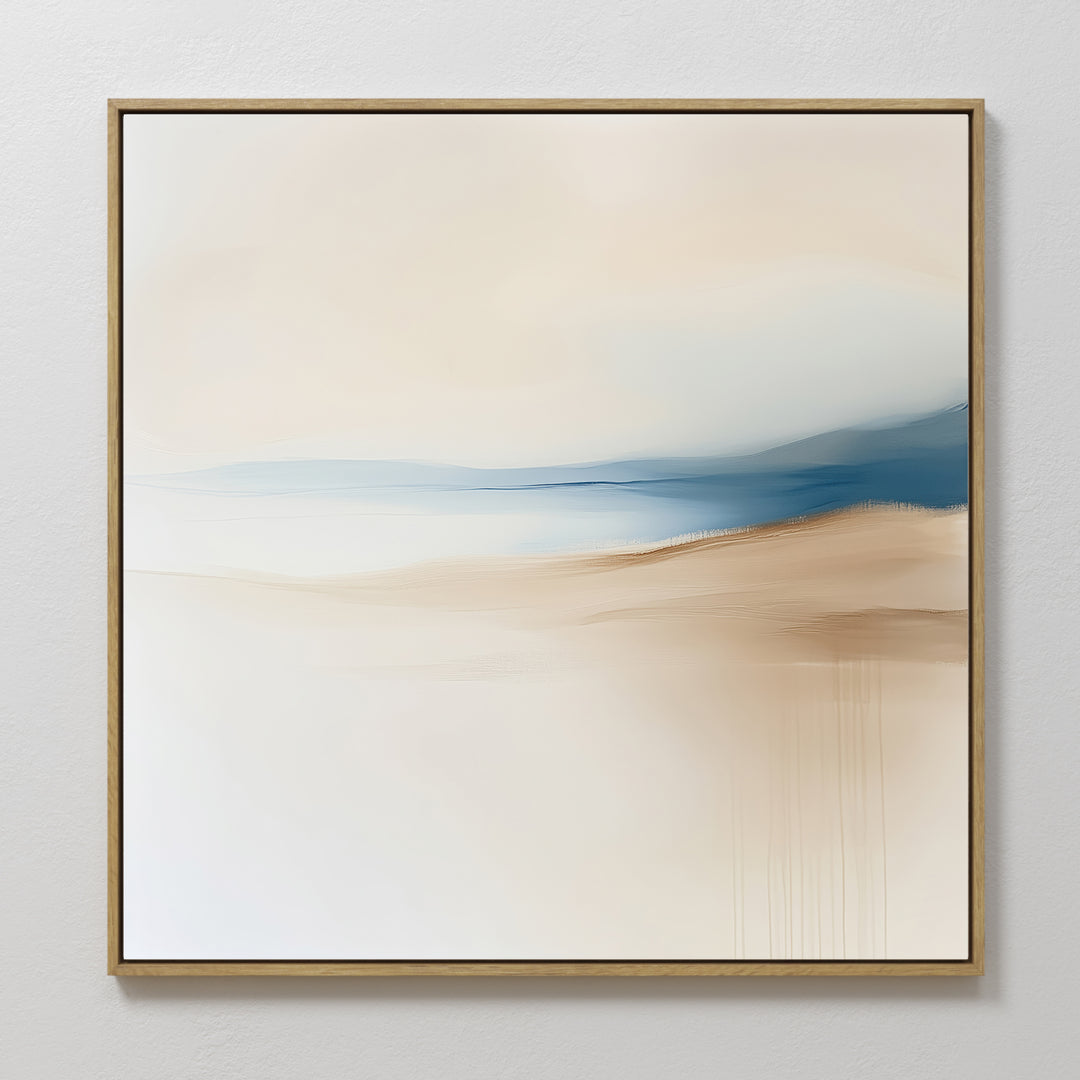 Golden Drift Canvas Art features minimalist abstract design with soft beige, white, and blue hues blending in serene gradients. Framed in a slim light wood frame, it’s perfect for adding an elegant touch to your living room’s white walls.