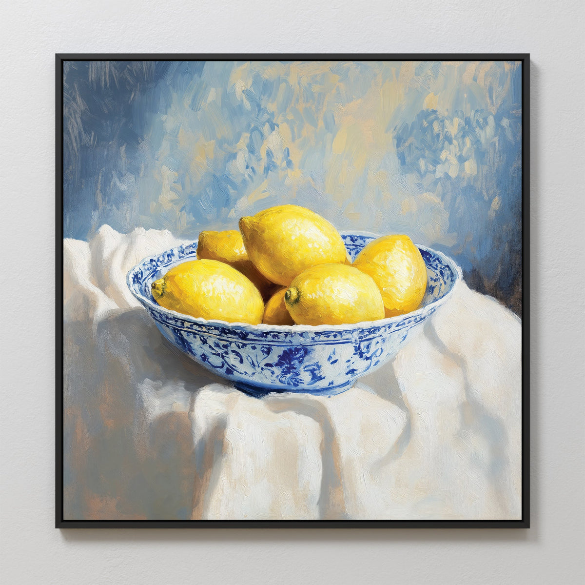 The Golden Fruit Canvas Art features a blue and white patterned bowl of lemons on a white cloth with a soft blue and yellow background. Perfect for vintage home decor, this print comes framed in sleek black.