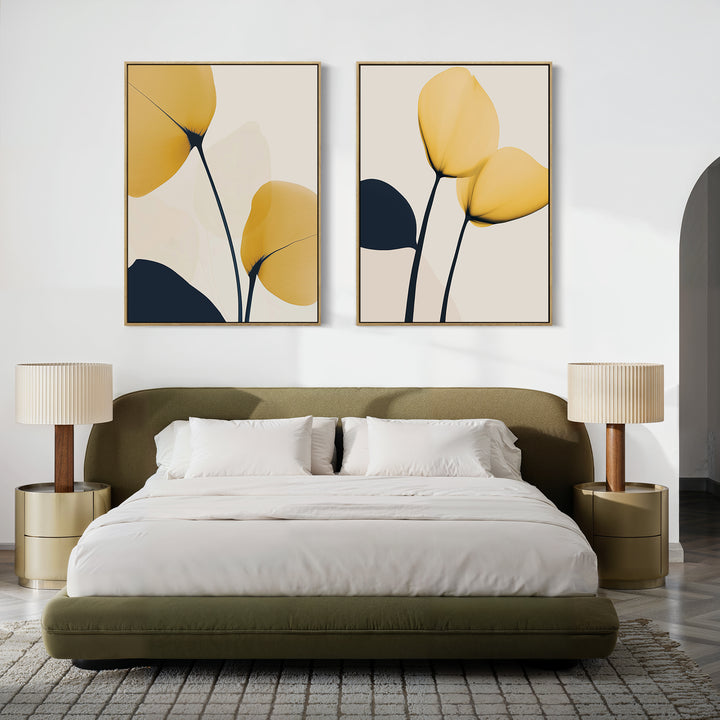 A modern bedroom with a green upholstered bed, white bedding, beige nightstands and lamps, and the Golden Leaves Set of 2 wall art featuring abstract yellow and navy petals above the bed.