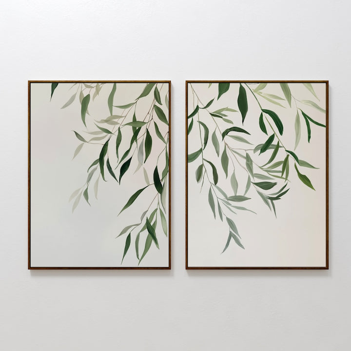 The Graceful Leaves Set of 2 features framed botanical prints with green leafy branches on light backgrounds. This minimalist wall art set brings a calming vibe, making it perfect for living room decor or any tranquil space.