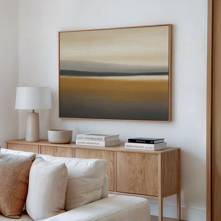 A modern living room features a wooden sideboard with books, a lamp, and bowl. Above it hangs the Honey Mesa Canvas Art in earthy tones. A light-colored sofa is partially visible in this contemporary decor setting.