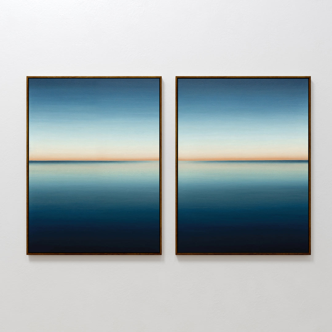 The Indigo Passage Set of 2 features minimalist framed wall art of calm water reflecting the sky in deep blue to peach tones—ideal for adding a tranquil, modern touch to your living room decor.