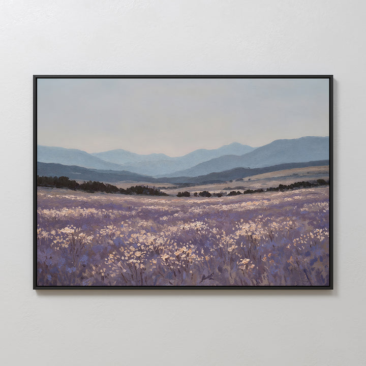 The Lavender Terrain Canvas Art features a serene field of purple wildflowers and white blooms with rolling hills and distant blue mountains under a cloudy sky, bringing minimalist elegance to any plain white wall.