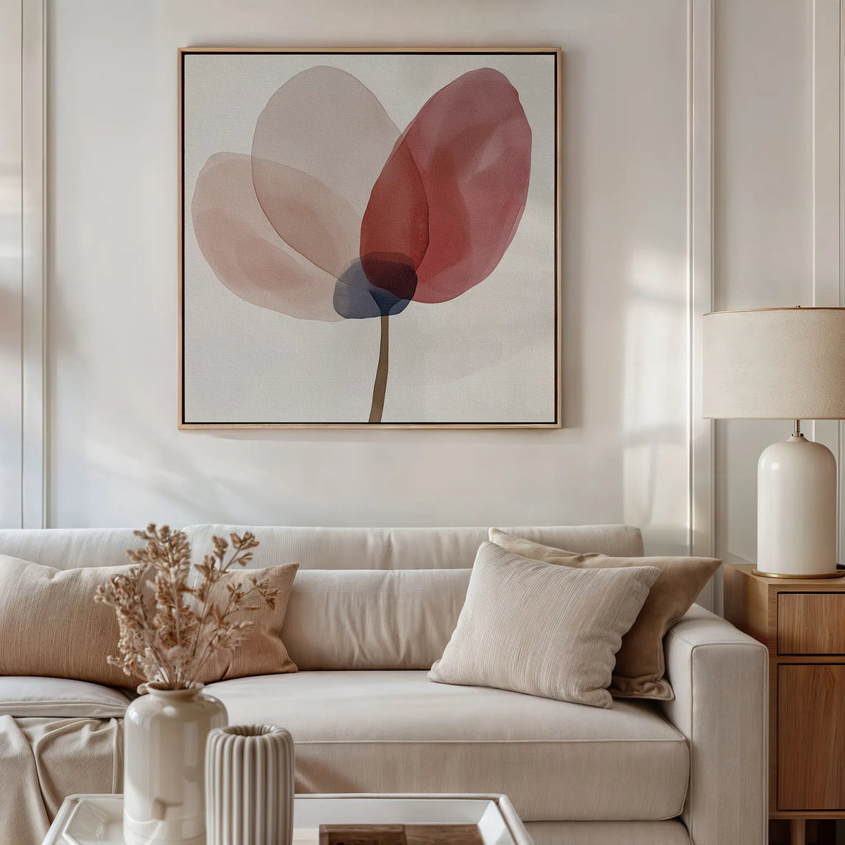 A modern living room with a white sofa, neutral cushions, a wooden side table with a cream lamp, dried flowers in a vase, and the Layered Bloom Canvas Art as floral wall art brings elegance to the space.