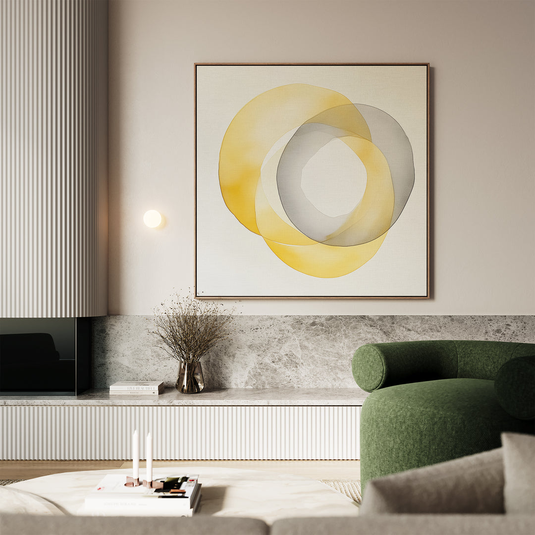 A modern living room with a green curved sofa, a marble shelf with books and a vase of dried branches, and the Lemon Light Canvas Art featuring overlapping yellow and gray rings on the wall.