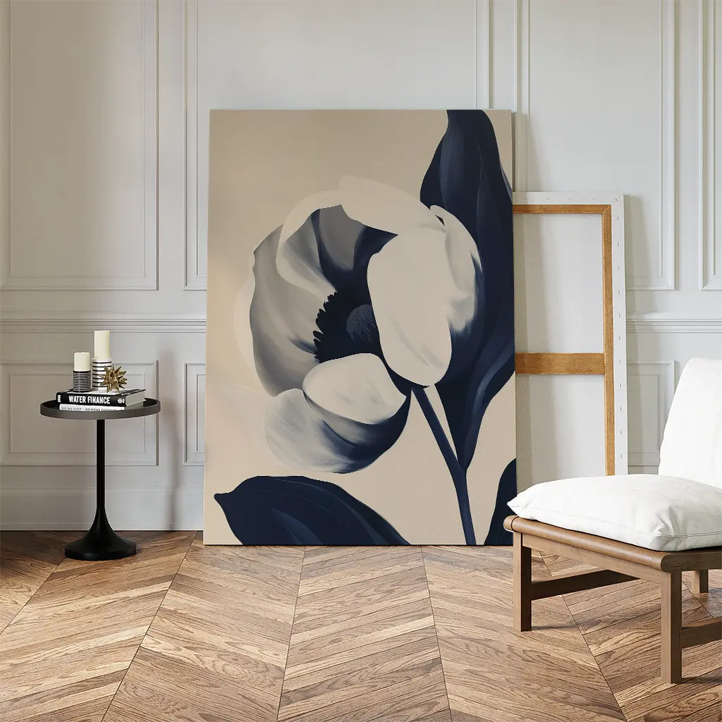 The Midnight Tulip Canvas Art, a large black and white floral piece, leans against the wall in a modern living room with herringbone floors, a round table with candles, and a white cushioned chair.