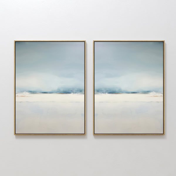 The Misty Morning Set of 2 features framed abstract paintings with soft, blurred shades of blue, white, and beige, evoking a calm sky over water. This minimalist wall art set brings a tranquil feel to any white wall.