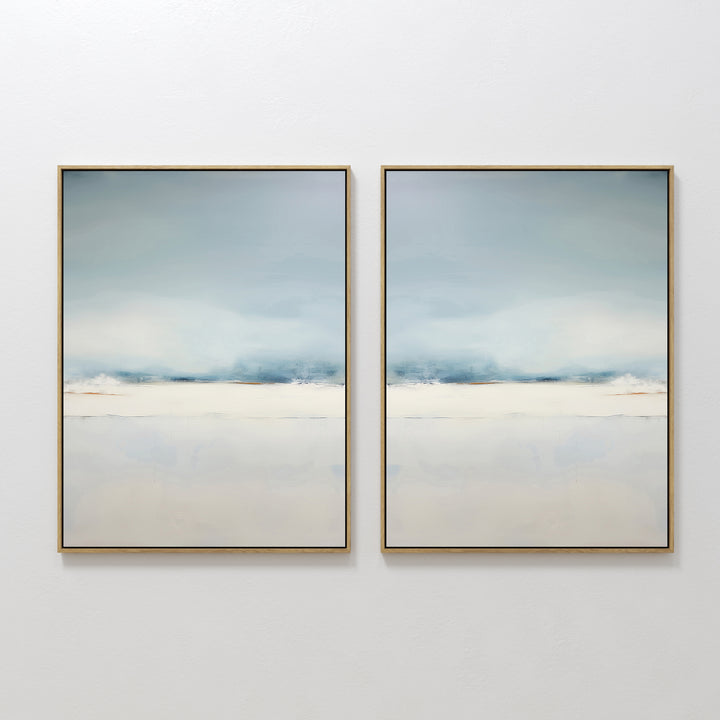 The Misty Morning Set of 2 features framed abstract paintings with soft, blurred shades of blue, white, and beige, evoking a calm sky over water. This minimalist wall art set brings a tranquil feel to any white wall.
