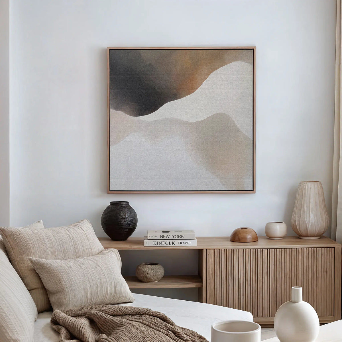 A modern, minimalist living room with a neutral color palette, featuring a beige sofa with cushions, a wooden sideboard with décor, and the Misty Silhouette Canvas Art as the focal point above.