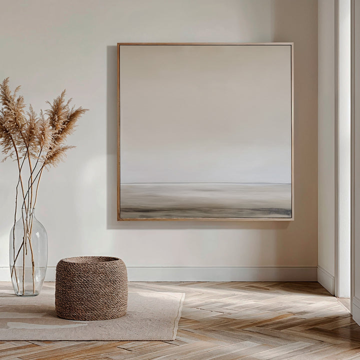 Minimalist living room featuring the Morning Mist Abstract Canvas Art as serene wall décor, a clear vase with dried pampas grass, a woven basket, and light wood herringbone flooring bathed in natural sunlight.