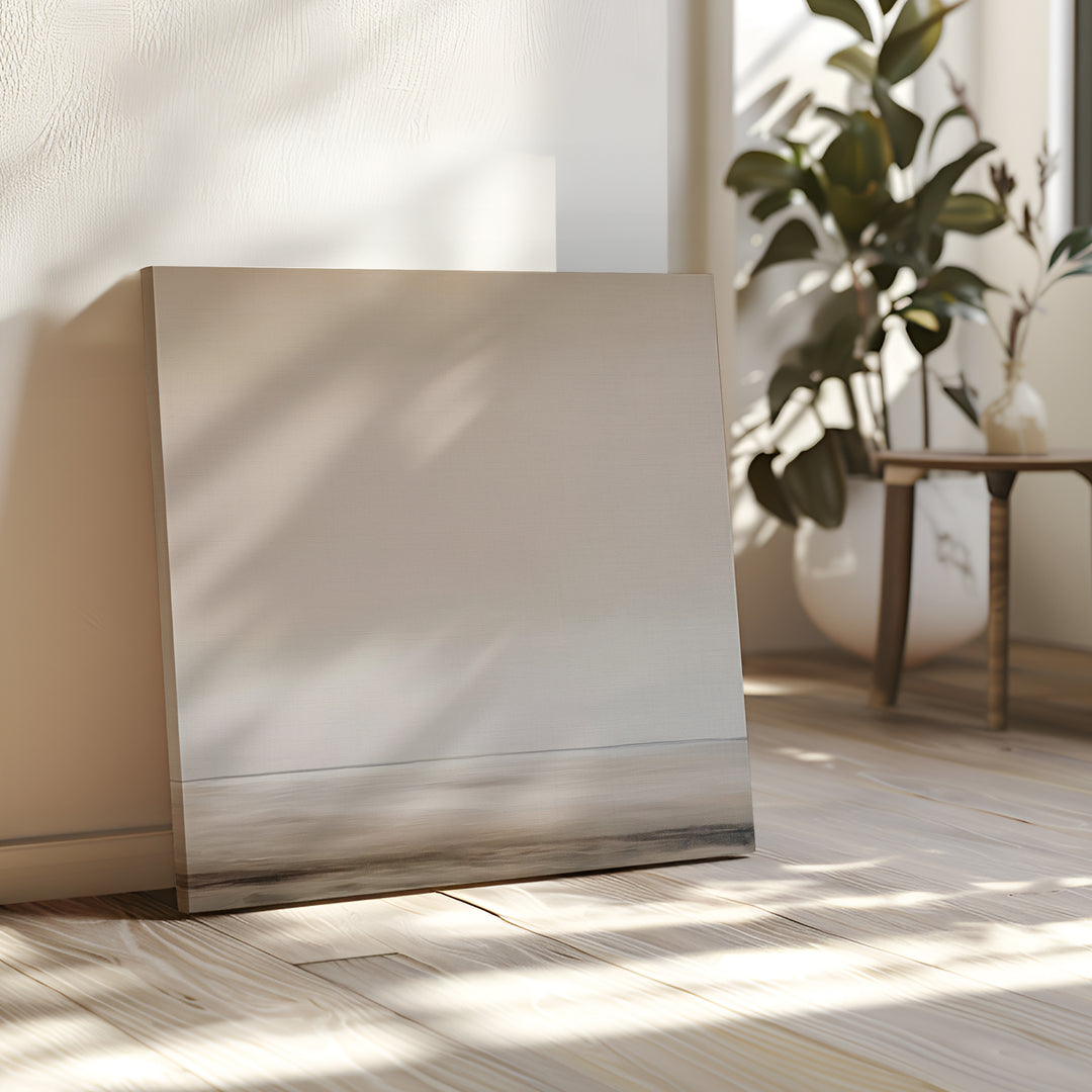The Morning Mist Abstract Canvas Art leans against a white wall in a sunlit room with wooden floors, a green potted plant, and a small table in the background, creating a minimalist vibe.