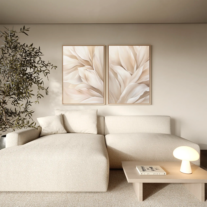 A cozy living room with a beige sectional, a small round lamp on a light wood coffee table, a leafy plant, and the Natural Texture Set of 2 abstract floral wall art bringing minimalist decor to the space.