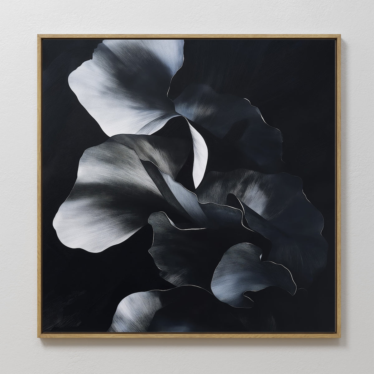 The Nocturnal Bloom Abstract Canvas Art showcases overlapping black, gray, and white floral petals on a dark background, elegantly framed and displayed on a white wall.