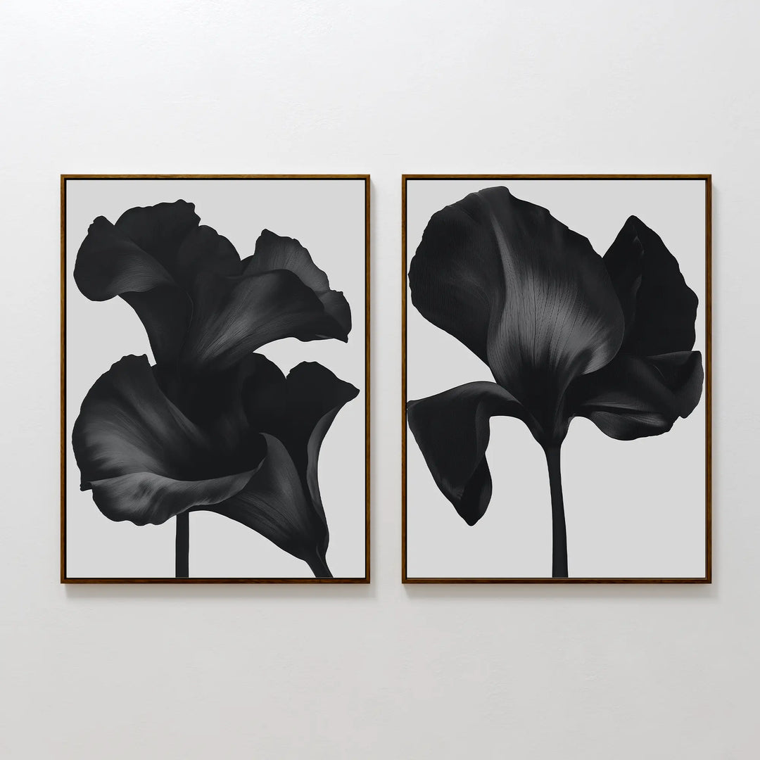 The Noir Bloom Set of 2 features framed black floral prints with detailed single blooms on light gray backgrounds, hung side by side—perfect contemporary wall art for any modern space.