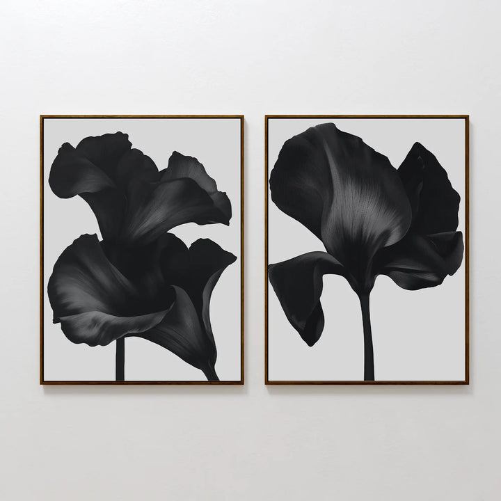 The Noir Bloom Set of 2 features framed black floral prints with detailed single blooms on light gray backgrounds, hung side by side—perfect contemporary wall art for any modern space.