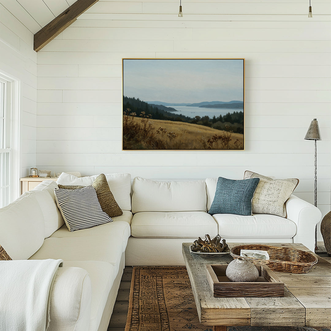 A bright, cozy living room with white shiplap walls, a large white sectional sofa, assorted pillows, a rustic wooden coffee table, and minimalist wall art—the Northern Silence Canvas Art—displayed above the couch.