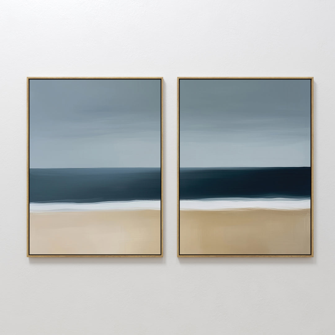 The Ocean Edge Set of 2 features framed abstract wall art with muted beige sand, deep blue water, and a gradient sky, creating a serene beach scene—perfect coastal decor for your living room.