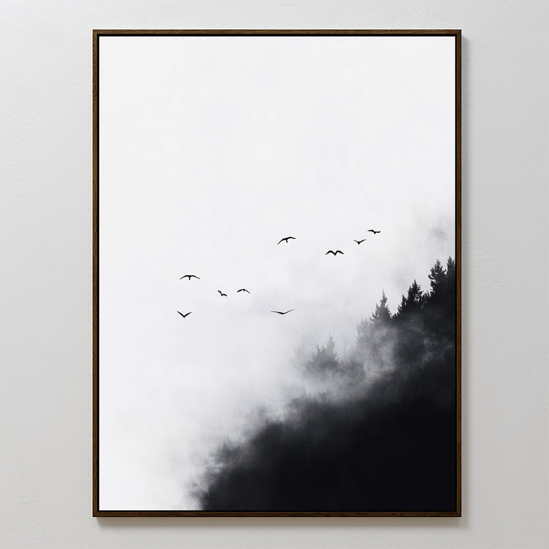 The Passing Pines Canvas Art features black bird silhouettes soaring above a misty forest with dark treetops, set on a white background and framed in a slim black frame—perfect for adding minimalist elegance to any space.
