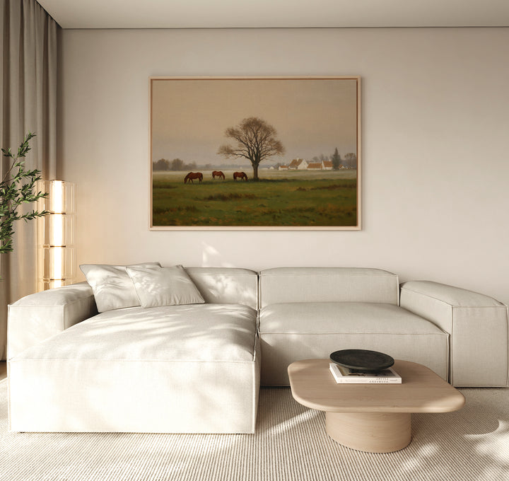 A modern living room with a light beige sectional, wooden coffee table, and countryside decor features the Pasture Morning Canvas Art, depicting horses grazing in a green field. Natural light enhances the tranquil rural charm of the space.