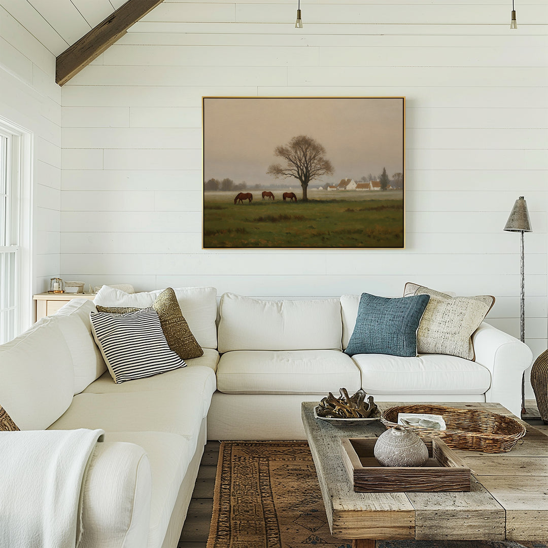A cozy living room with a white sectional sofa, assorted throw pillows, a wooden coffee table with decor, and the Pasture Morning Canvas Art featuring horses in a field displayed above the seating area.