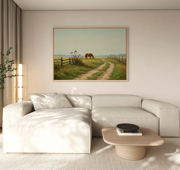A modern living room with a light beige sectional sofa, a wooden coffee table, and rustic décor—a large Pasture Path Canvas Art featuring a horse and country path—hanging above the couch.
