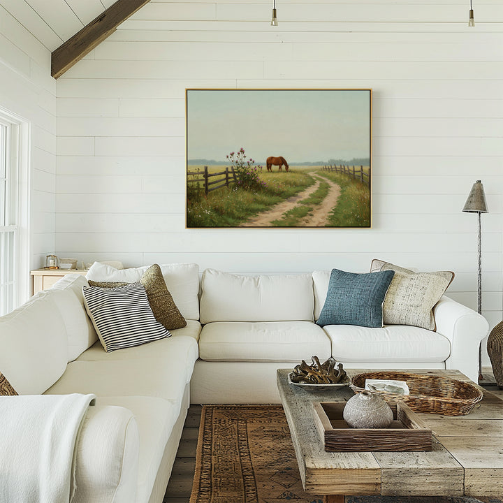 A cozy living room with a white sectional sofa, rustic wooden coffee table, textured pillows, and countryside accents—Pasture Path Canvas Art hangs on the white shiplap wall above the sofa.