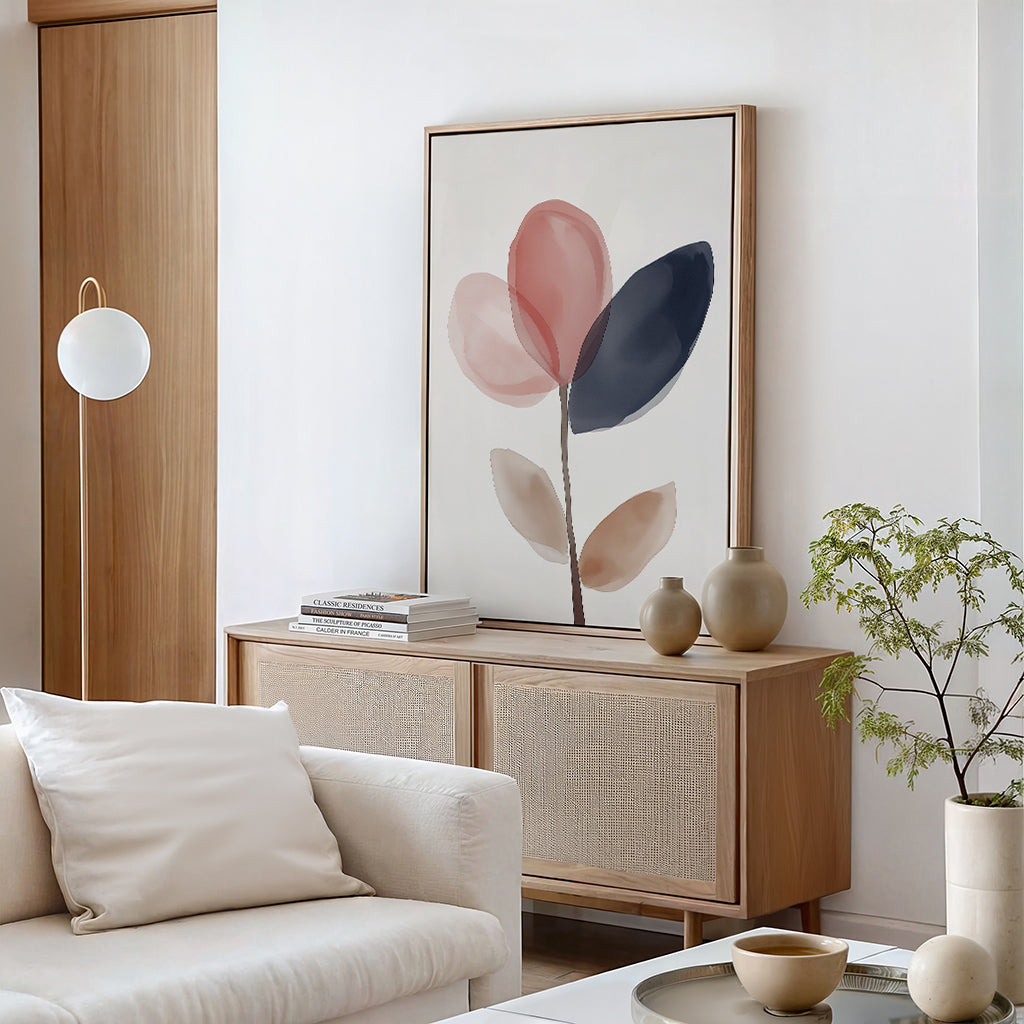 A modern living room features a light wood sideboard, Petal Breeze Canvas Art, ceramic vases, a small green plant, and a white sofa with neutral cushions. Soft, natural tones create a minimalist and serene atmosphere.