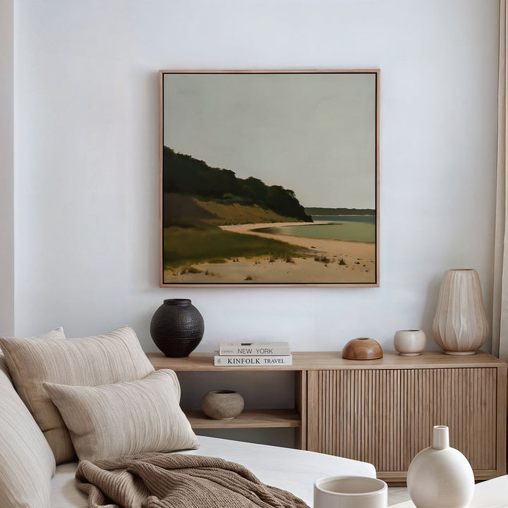 A minimalist living room with a beige couch and wooden sideboard features Quiet Bend Canvas Art—a framed landscape beach scene—hung above, offering refined living room decor inspiration.