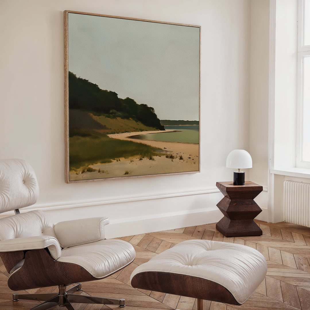 A modern, minimalist room features a white leather lounge chair and ottoman, a geometric wooden side table with a white lamp, and Quiet Bend Canvas Art as striking living room decor on the wall.
