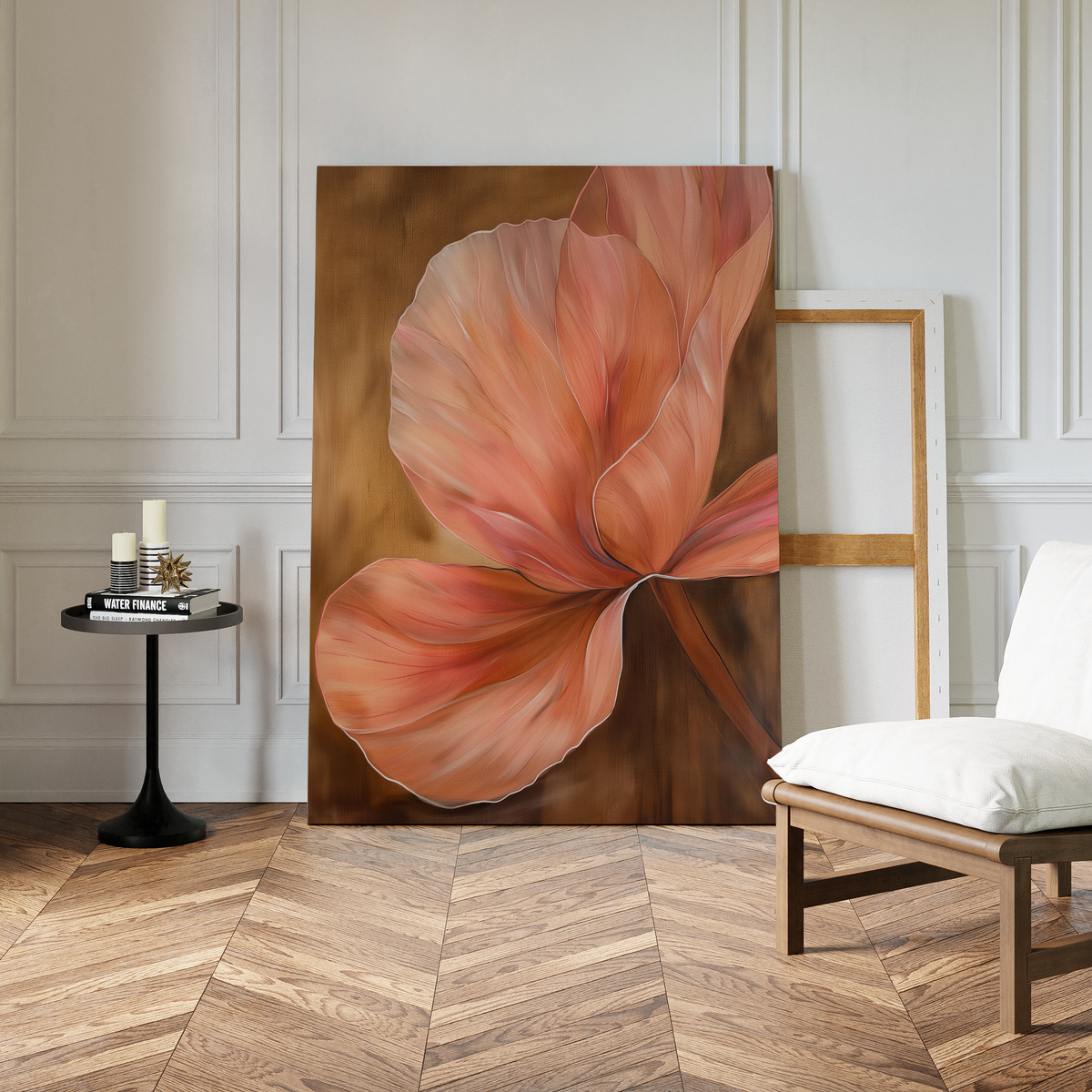 The Blush Petals Abstract Canvas Art, showcasing pink and orange flower petals, leans against a wall in a modern room with parquet flooring, white paneled walls, a white chair, and a round table with candles.