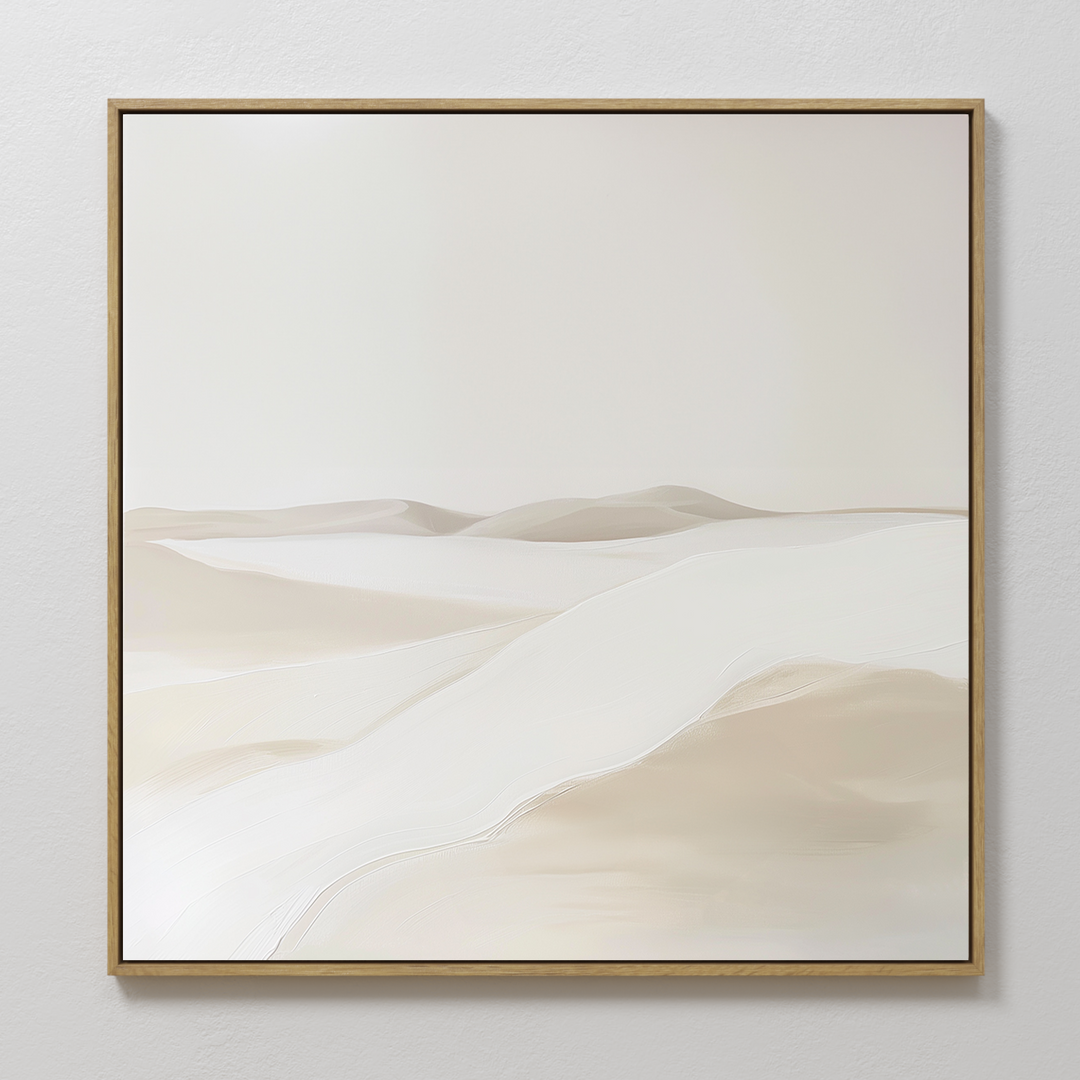 Misty Vale Abstract Canvas Art features soft, rolling sand dunes in neutral beige and white tones, framed in thin gold and displayed on a light wall—ideal for creating a serene atmosphere in your living room or bedroom.