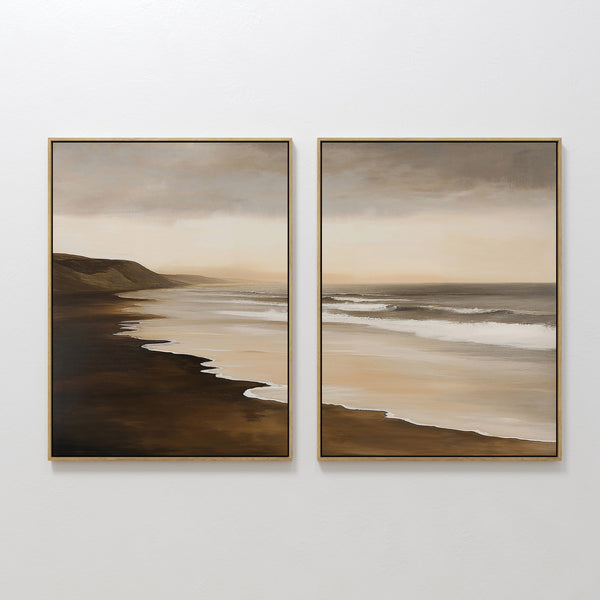 The Sandy Shoreline Set of 2 features framed beach canvases depicting gentle waves, sandy shores, distant hills, and a muted sky—perfect coastal wall art for stylish living room decor.