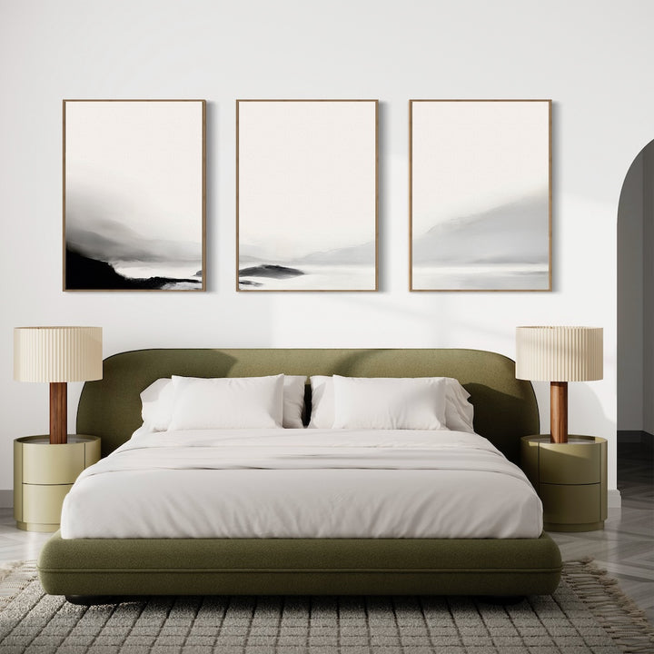 Minimalist bedroom with an olive green bed, white bedding, two beige lamps on matching nightstands, and the Serenity Peaks Set of 3 abstract landscape paintings in neutral tones above the bed for a serene, modern look.