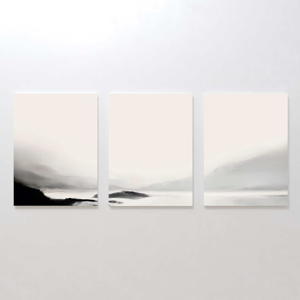 The Serenity Peaks Set of 3 features minimalist, monochrome landscape paintings with soft black, gray, and white gradients depicting foggy mountains and tranquil water in a modern style, perfect for a serene wall display.