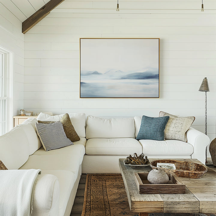 A cozy living room with white shiplap walls, a large white sectional sofa, assorted pillows, a rustic wooden coffee table with decor, and the Silent Glaciers Canvas Art hanging as minimalist wall art above the couch.