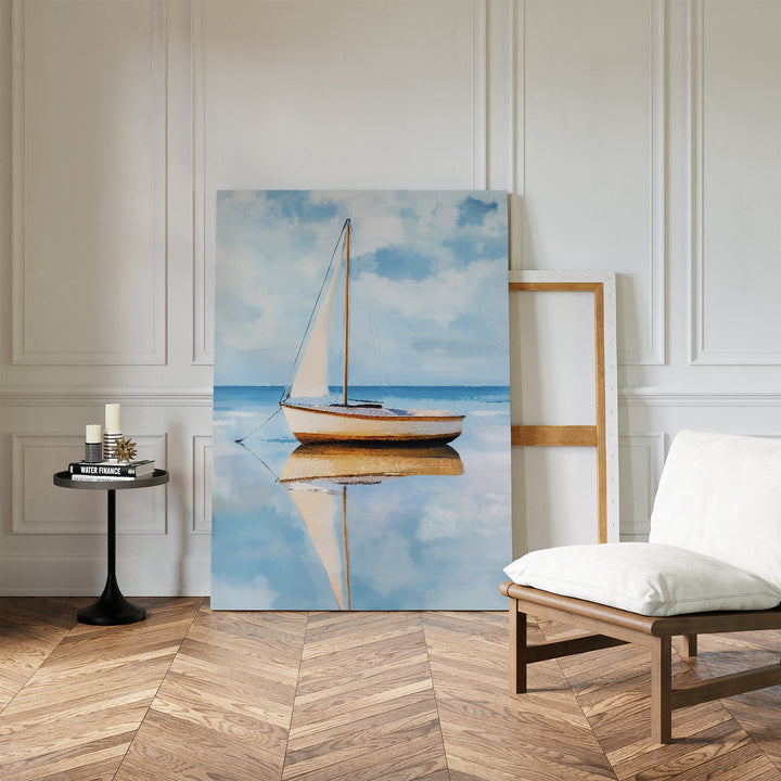 The Skybound Reflection Canvas Art, featuring a sailboat on calm water in minimalist style, leans against a white paneled wall in a tranquil room with herringbone floors, a cushioned chair, and a round table with candles.