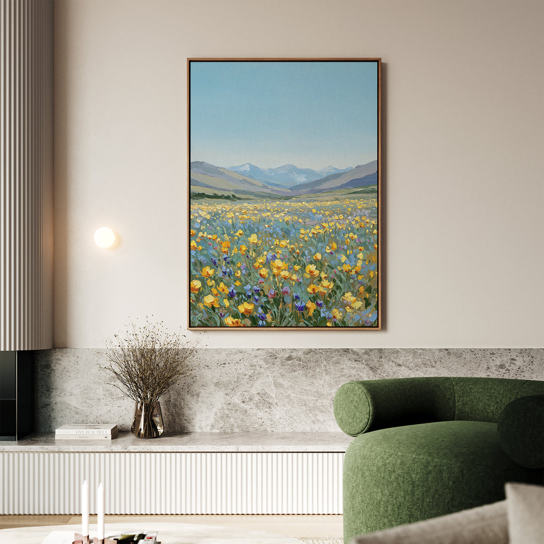 A modern living room featuring a green chair, marble bench, dried flowers in a vase, and the Skyview Field Canvas Art—a vibrant wildflower field with mountains and blue sky—adds charm to the beige wall.