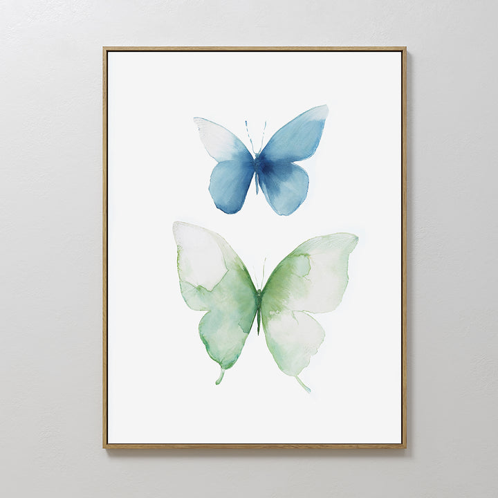Soft Flight Canvas Art: A Nordic Park-inspired minimalist wall print with two watercolor butterflies, one blue and one green, set against a white background in a slim gold frame.