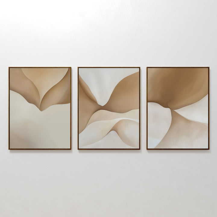 The Soft Sands Set of 3 features minimalist abstract paintings with soft, flowing beige and brown shapes, each in a slim dark frame, displayed side by side on a plain white wall.