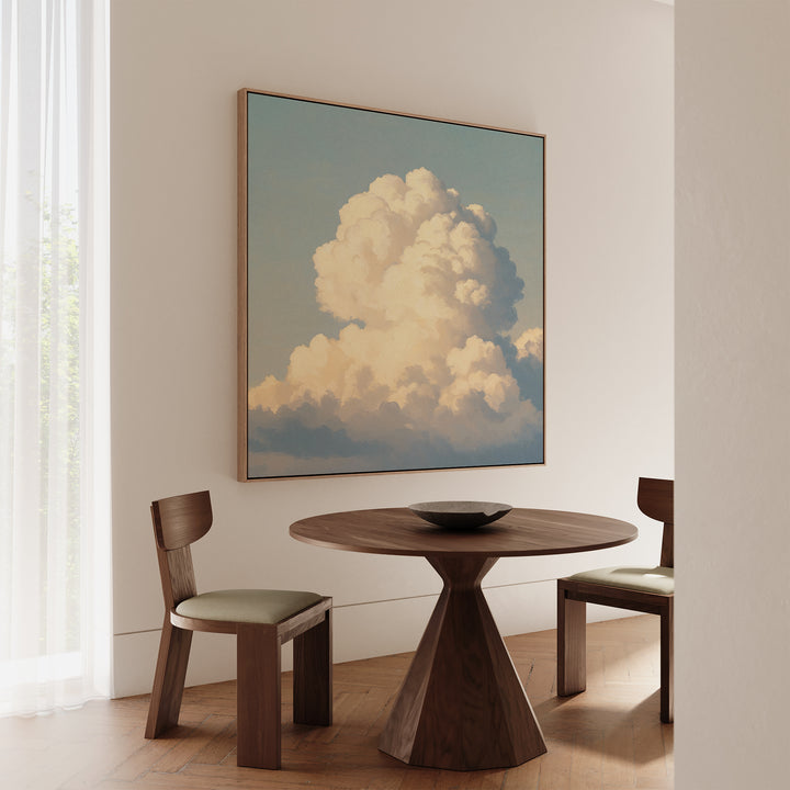 A minimalist dining area features a round wooden table, two matching chairs, and the Soft Skies Rising Canvas Art on the wall. Sheer curtains diffuse natural light, creating a serene ambiance.