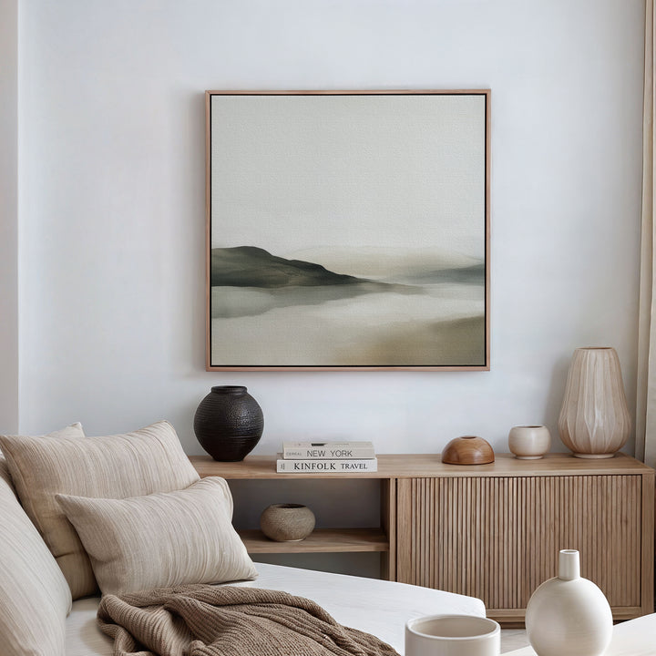 A minimalist living room features a beige sofa, neutral cushions, wooden sideboard, decorative vases, books, and the Soft Valley Canvas Art. Sheer curtains let in natural light, creating an inviting space for minimalist decor lovers.