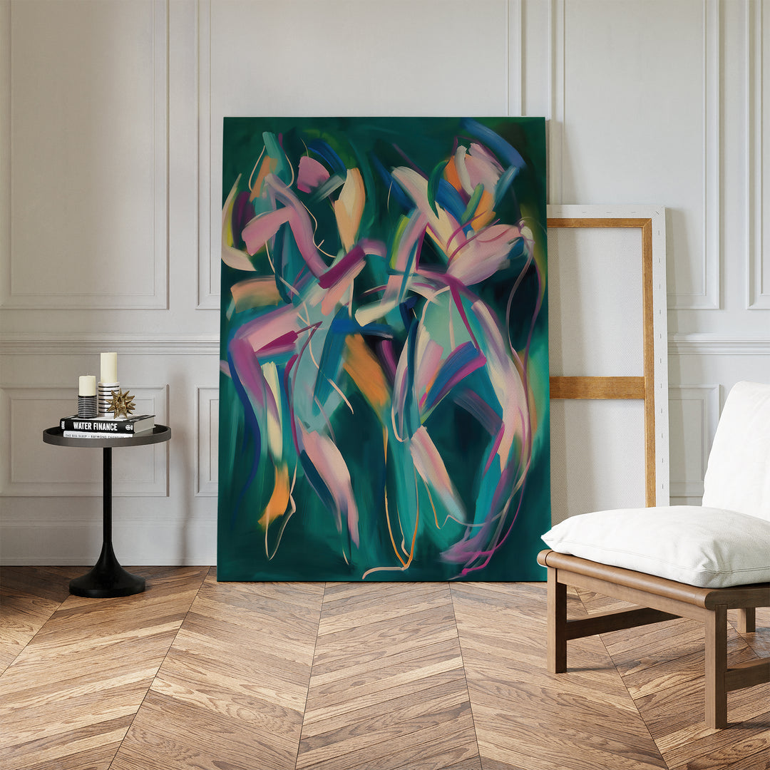 The Spiralling Forms Abstract Canvas Art, with its vibrant design, leans against a white wall in a bright room featuring wood parquet floors, a white chair, a black side table with candles and books, and an empty wooden frame nearby.
