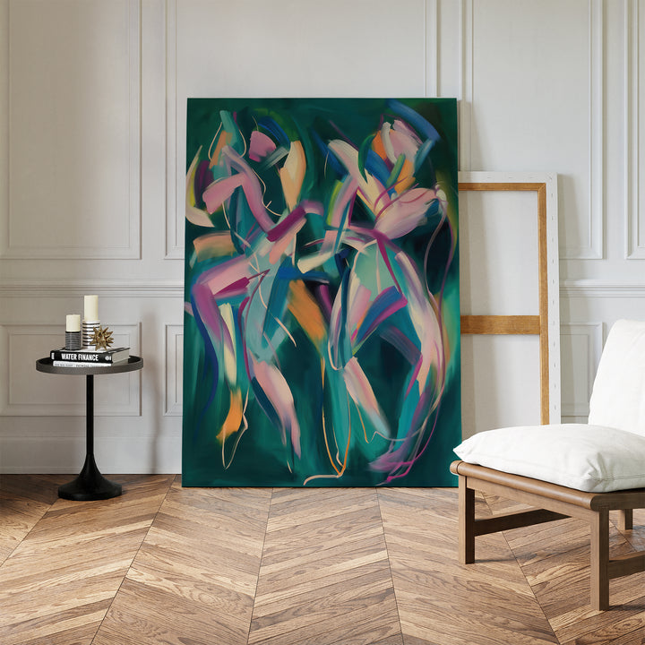 The Spiralling Forms Abstract Canvas Art, with its vibrant design, leans against a white wall in a bright room featuring wood parquet floors, a white chair, a black side table with candles and books, and an empty wooden frame nearby.