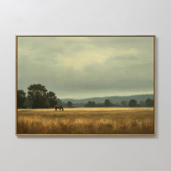 The Still Morning Canvas Art features a framed countryside scene with a lone horse grazing in a golden field beneath cloudy skies, distant trees, and soft lighting for a tranquil, rural touch.