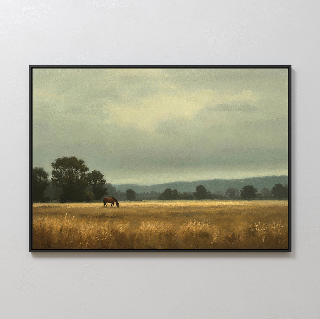 Still Morning Canvas Art: A framed wall art piece featuring a peaceful rural landscape with a brown horse grazing in a golden field, surrounded by trees and distant hills beneath a cloudy sky.
