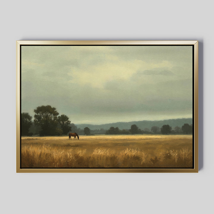 The Still Morning Canvas Art captures a serene landscape of a lone brown horse grazing in a golden field, framed by distant trees and hills beneath a cloudy, pale sky.
