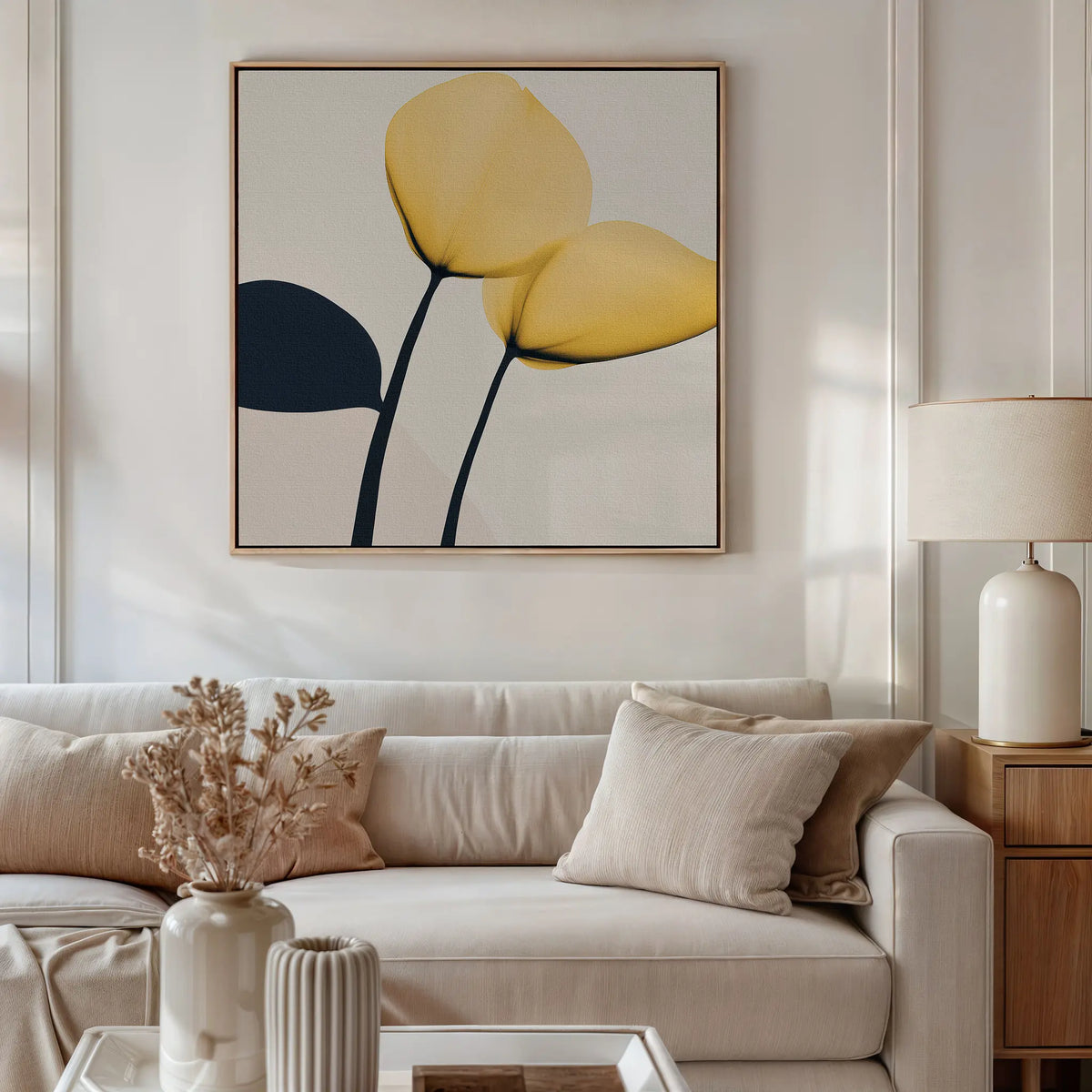 A modern living room with a beige sofa, neutral pillows, a wooden side table and lamp, dried flowers in a vase, and the Sunny Flora Canvas Art featuring yellow blooms displayed above the seating area.