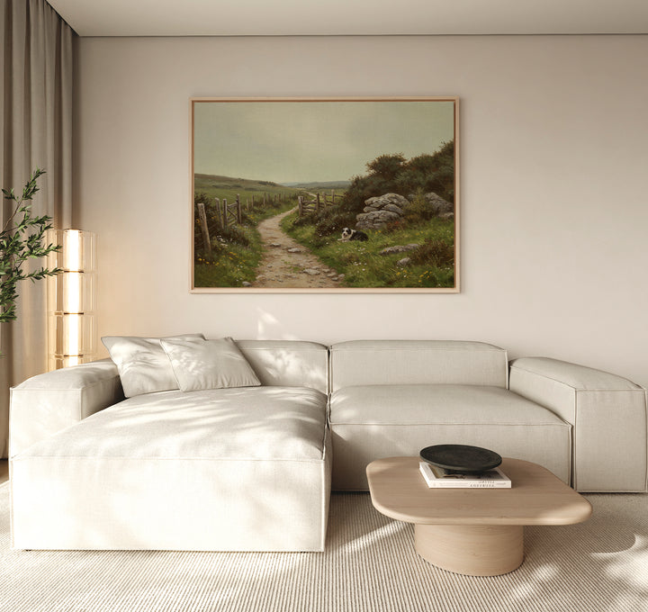 A modern living room features a light beige sectional sofa, wooden coffee table, and The Watchful Path Canvas Art depicting a rural path. Beige curtains filter sunlight, while rustic decor includes a tall plant in the corner.