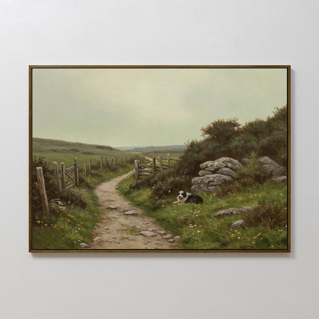The Watchful Path Canvas Art is a framed painting of a rural landscape, showing a black and white dog resting beside a winding dirt path amid grassy fields and rocks under a cloudy sky—perfect countryside wall art.