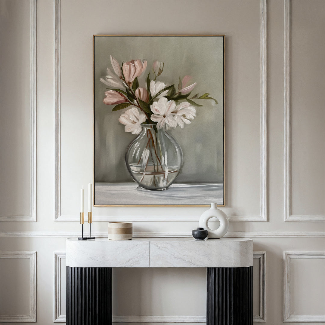 The Vase & Grace Canvas Art, featuring white and blush flowers in a glass vase, adds an elegant minimalist touch above a marble console styled with candles and decor—perfect for refined living room spaces.